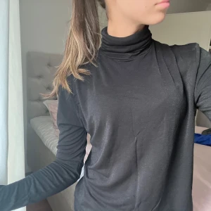 Filippa K tröja - Säljer en svart långärmad tröja med polokrage och glitter i tyget. Den är från Filippa K i stolen S. Jag säljer den då den tyvärr inte kommer till någon användning.❣️Nypris ca 1300