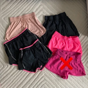 Ett kit med fem stycken träningsshorts  - * Ljusrosa träningsshorts. XS/34. * Svarta shorts, rosa detaljer - Storlek 38, passar storlek 32-38. * Svarta träningsshorts, rosa detaljer. XS/34.  Fint skick, lite slitage på trycket. * Svarta shorts. XS. * Rosa träningsshorts. Storlek XS/34.
