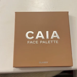 Face Palette från CAIA - Säljer en superfin face palette från CAIA i nyansen 'Classy'. Den innehåller contour, bronzer, blush och highlighter. Perfekt för att skapa en komplett look! Paletten har en inbyggd spegel, vilket gör den perfekt för touch-ups när du är på språng. Den är helt ny