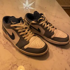 Snygga Nike Air Jordans i blått och vitt med klassisk snörning. Skorna har en ikonisk design med perforerade detaljer på tån och en robust sula för extra grepp. 