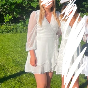 Studentklänning - Vit sommarklänning från bubbleroom 🌸Endast använd en gång, jättefint skick. Storlek 40 men passar mig som brukar ha 38. Klänningen har snören som man knyter i midjan samt genomskinliga ärmar. 