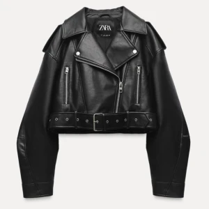 Svart skinnjacka från Zara - Snygg svart skinnjacka från Zara med dragkedja och bälte i midjan. Jackan är croppad och har långa ärmar samt stiliga detaljer.