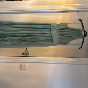 Ljusgrön byxdress från Zara - Elegant ljusgrön byxdress från Zara med hög hals och smala axelband. Byxdressen har ett plisserat tyg och en bred midjedetalj som ger en smickrande silhuett. Perfekt för speciella tillfällen. Helt oanvänd, prislapp finns kvar