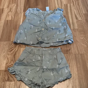 Grön blommigt set från H&M - Säljer ett grönt set med blommönster från H&M. Shortsen har elastisk midja och volangdetaljer vid bensluten. Perfekta för varma sommardagar!