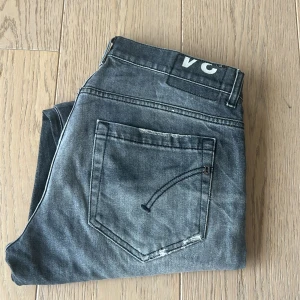 Grå jeans med slitningar DONDUP George skinny fit  - Snygga grå jeans med coola slitningar och en avslappnad look. De har en klassisk femficksdesign och en diskret logga på baksidan. Perfekta för en casual stil. DONDUP GEORGE skinny fit size 34