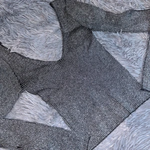 Grå glittrig tröja - Säljer en snygg glittrig tröja med lång ärm och v-ringning. Perfekt för både vardag och fest. Perfekt inför nyår.