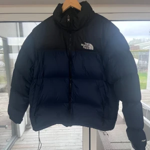 The North Face jacka - The north face 1996 retro nuptse dunjacka Säljer en snygg och varm dunjacka från The North Face i svart och mörkblått. Jackan har en dragkedja och är perfekt för kalla vinterdagar❄️. Den är i bra skick med en liten lagning på baksidan längst ner. Nypris: 3900kr säljer för: 950kr. Kontakta vid minsta fundering! 