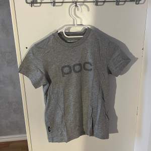 Säljer en grå t-shirt från POC i storlek 8-10 år / 140. Den är i mycket bra skick och har en enkel design med POC-loggan tryckt på framsidan. Perfekt för vardagsbruk eller träning. Bekvämt material. Aldrig använd.