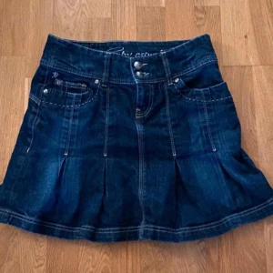 Demin Vintage Jeanskjol från DC by Esprit - Snygg jeanskjol från DC by Esprit i mörk denim. Kjolen har en klassisk femficksdesign och dekorativa sömmar. Perfekt för en avslappnad vardagslook eller en utekväll. Märket 'Authentic Denim Since 1998' ger en cool vintagekänsla.