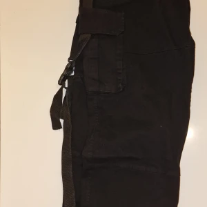 Svarta cargobyxor från Weakgoods - Snygga svarta cargobyxor från Weakgoods med praktiska fickor och justerbara resårband på sidorna. Perfekta för en avslappnad stil. Garderobsrensning så kika gärna in övriga auktioner