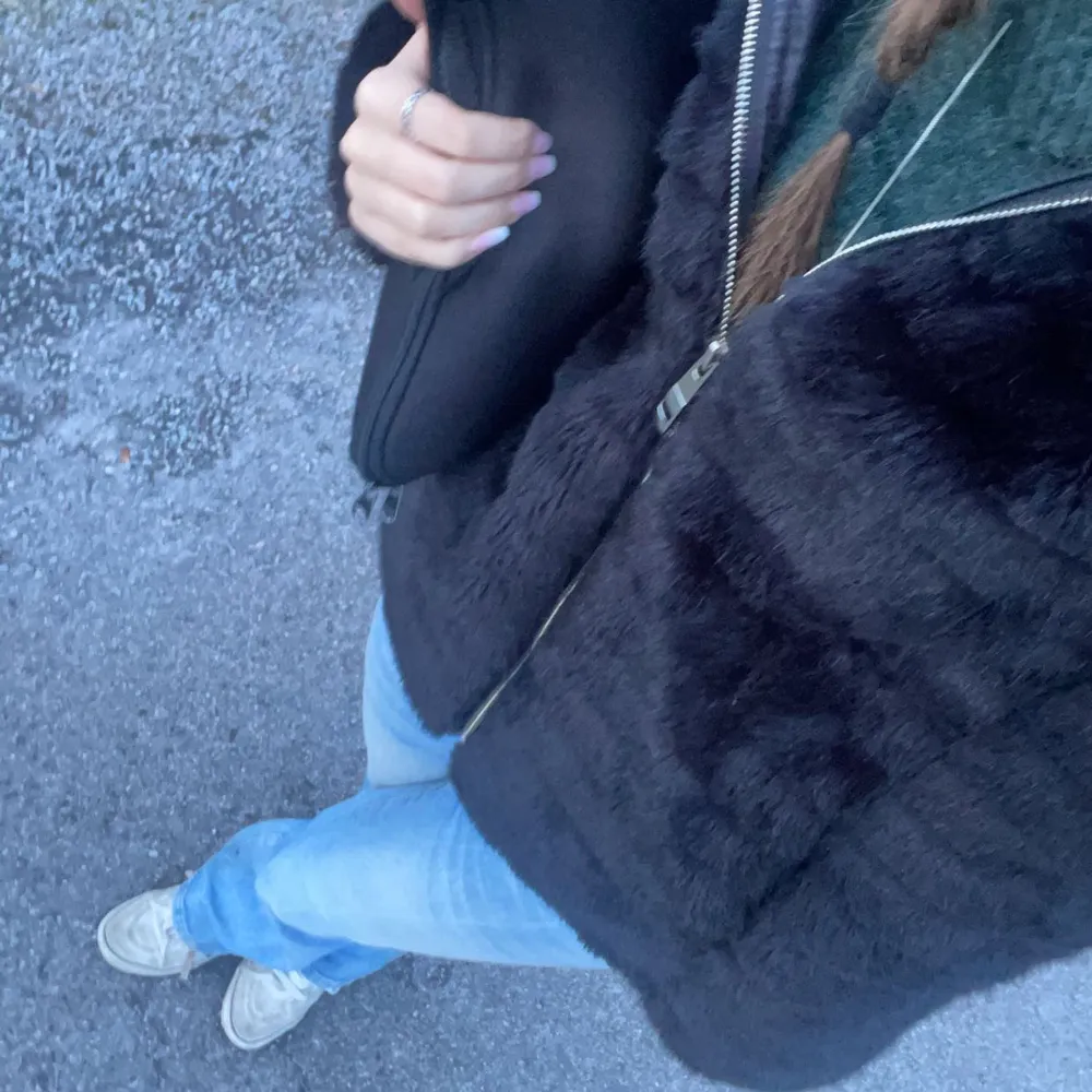 Snygg svart pälsjacka med dragkedja framtill. Perfekt för kyligare dagar och ger en lyxig känsla. Jackan har en normal passform och är lätt att matcha med olika outfits.. Jackor.