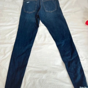 Mörkblå skinny jeans - Snygga mörkblå skinny jeans med slitningar på knäna och fransiga benslut. Perfekta för en trendig look.