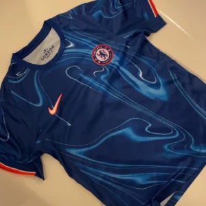 Äkta Chelsea tröja - Snygg blå Chelsea fotbollströja från Nike med ett unikt mönster och klubbens emblem på bröstet. Perfekt för fans som vill visa sitt stöd. Säljer tröjan för att jag fick tröjan i julklapp men den passar inte mig längre!