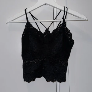 Svart spetslinne - Snygg svart spetslinne med 2 smala axelband och vacker spetsdetalj. Den har en croppad passform och en elegant design. Den är även vadderad. ALDRIG ANVÄND!