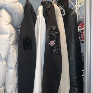 Svart glansig jacka från Moncler - Snygg svart glansig jacka från Moncler med dragkedja och huva. Jackan har långa ärmar och en quiltad design som ger en modern look. Perfekt för kyligare dagar. Storlek är S