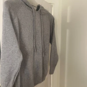 Grå hoodie i bomull - Säljer en stilren och bekväm grå hoodie i bomull. Perfekt för både höst och vinter. Den har långa ärmar och en klassisk huva med dragsko. Passar till alla tillfällen när du vill känna dig avslappnad och varm. Helt oanvänd!