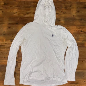 Ralph Lauren hoodie  - Säljer en vit hoodie från Ralph Lauren i bra skick. Den har en klassisk design med en liten broderad logga på bröstet. Perfekt för en avslappnad stil och passar till alla säsonger. Ganska tunn material i storlek M. Inga defekter 