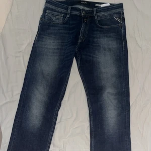 Mörkblå jeans från Replay - Snygga mörkblå jeans från Replay med klassisk femficksdesign och dragkedja . De har en diskret tvättad look och märkesdetaljer på bakfickan. Perfekta för en avslappnad stil. Tveka inte på att höra av dig om du har någon fråga.🤗