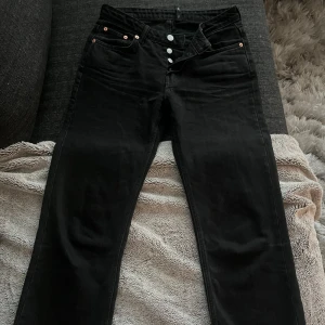 Svarta jeans från Weekday - Snygga svarta jeans från Weekday med knappgylf och klassisk femficksdesign. Perfekta för en stilren look. Tillverkade i slitstarkt material för en bekväm passform. Dessa byxor motsvarar storleken EX eller en liten S 