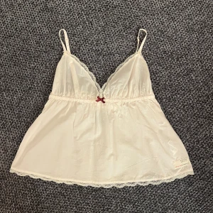 Ljusrosa spets linne från odd molly  - Ljusrosa linne med spetsdetaljer och en liten röd rosett framtill. Toppen har smala axelband och en broderad logga på baksidan. Linnet är väldigt ljusrosa vilket framgår tydligare på sista bilden! Skriv om ni har några frågor😊