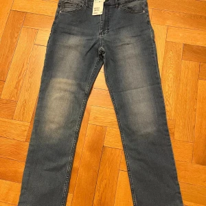 Blå slim fit jeans med croppad benlängd - Snygga blå slim fit jeans med croppad benlängd. Perfekta för en stilren look. De har en klassisk femficksdesign och en bekväm passform.