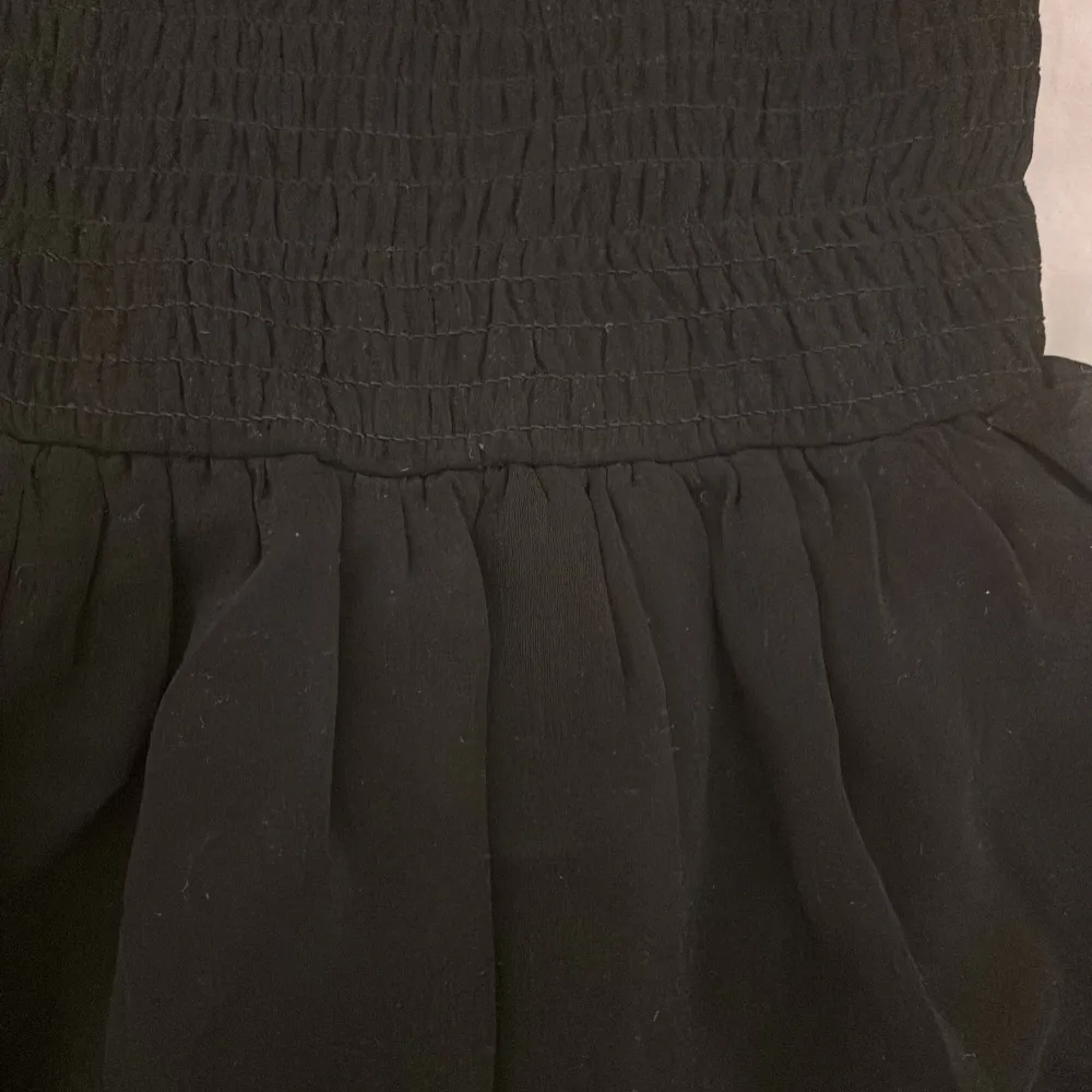 Snygg svart kjol från KappAhl med volangdetaljer. Kjolen har en elastisk midja för bekväm passform och är perfekt för olika tillfällen. Den är tillverkad i ett lätt och luftigt material.. Hameet.