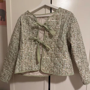 Grön quiltad jacka med knytband - Säljer en unik grön quiltad jacka med ett diskret mönster och knytband framtill. Jackan har långa ärmar och en rund halsringning. Köpt i Spanien och ingen storlek! Men har vanligtvis runt S-M❤️