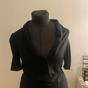 Bolero - Snygg svart bolero med en elegant krage och knäppning framtill. Perfekt för en stilren look.