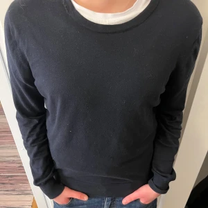 Svart tröja från J.Lindeberg - Säljer en stilren svart tröja från J.Lindeberg. Tröjan har en klassisk design med rund hals och långa ärmar. Perfekt för en minimalistisk look. Den är storlek M men sitter som en S beroende på hur lång man är. 