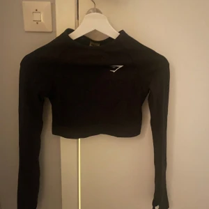 Svart croppad tröja från Gymshark - Svart långärmad croppad träningströja Gymshark. Aldrig använd, så fint skick. Finns hål för tummen längst ner på tröjan.