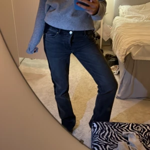 Svarta jeans med sidodetalj - Snygga svarta jeans med en cool sidodetalj i form av en mörkare rand. De har en klassisk femficksdesign och en knappgylf. Perfekta för en avslappnad stil.