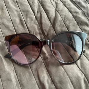 Solglasögon från Gucci - Snygga solglasögon från Gucci med en klassisk rund form och mörka linser. Loggan saknas på ena sidan