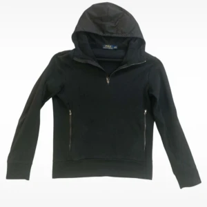 Svart hoodie från Polo Ralph Lauren - Snygg svart hoodie från Polo Ralph Lauren med dragkedja och huva. Perfekt för en avslappnad stil. Den har långa ärmar och praktiska fickor med dragkedja. Prutbar vid smidig affär.