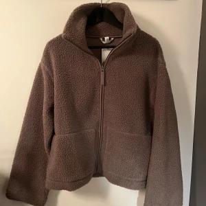 Brun teddyjacka med dragkedja - Mysig brun teddyjacka från H&M. Populär och slutsåld. Storlek L men som en M. Helt oanvänd med lappen kvar. 