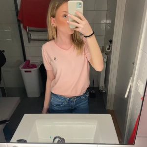 Rosa t-shirt från Ralph Lauren - Säljer en ljusrosa stickad t-shirt från Ralph Lauren med en liten broderad logotyp på bröstet. T-shirten har en klassisk passform och korta ärmar. Perfekt för en avslappnad stil. Aldrig använd då jag fick den i present och det inte riktigt är min stil. Pris kan diskuteras💖