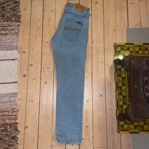 Nudie Jeans  - Säljer ett par klassiska blå jeans från Nudie. De har en straight passform och är högmidjade med fem fickor och knappgylf.  Strlk:33 L32