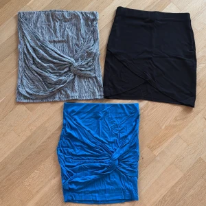 Tre kjolar i olika färger - Klädpaket tre minikjolar i olika färger. En svart kjol med enkel design, en blå kjol med knytdetalj och en gråmönstrad kjol med knytdetalj framtill. All passar small/medium. 