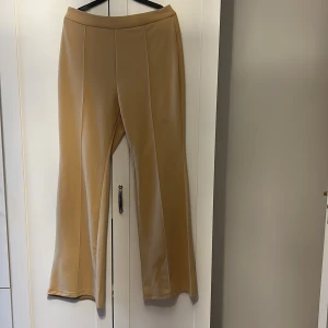 Beige byxor - Snygga beige byxor med hög midja och rak passform. Perfekta för en stilren look. Tillverkade i ett mjukt material som ger en bekväm känsla hela dagen.