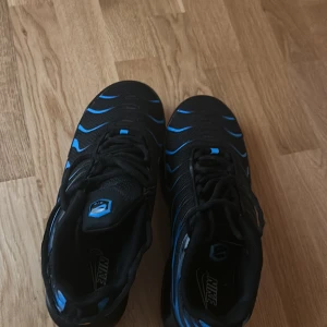 Nike sneakers i svart och blått - Snygga Nike skor i svart med blå detaljer. Skorna har en sportig design med synlig dämpning i sulan. Lådan finns, pris diskuteras 