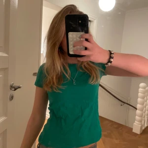 Grön t-shirt från Zara - Säljer en snygg grön t-shirt från Zara i storlek XS. Perfekt för en avslappnad stil. T-shirten har en enkel design med korta ärmar och rund hals.