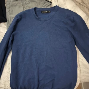 Blå tröja från J.Lindeberg - Säljer en stilren blå tröja från J.Lindeberg. Tröjan har en diskret logga på bröstet och är tillverkad i ett mjukt material. Perfekt för en avslappnad men snygg look. Det står M i tröjan men den passar mycket bättre på storlek S 