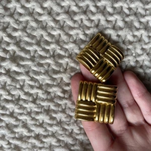 Guldiga örhängen i fyrkantig design - Snygga guldiga örhängen med en unik fyrkantig design. De har en ribbad struktur som ger en modern och stilren look. Perfekta för att lyfta vilken outfit som helst. Använda en gång. Nypris 328 kr (inkl frakt) 