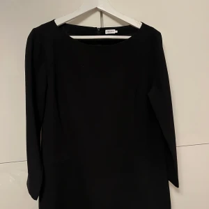 Svart klänning från Filippa K - Elegant svart klänning från Filippa K med båtringning och långa ärmar. Storlek L. Perfekt för en stilren look. Klänningen har en dragkedja i ryggen. Nypriset var närmare 2000:-. Perfekt för fester och nyår. Jättefint skick! Hör av er vid frågor!