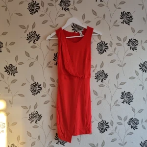 Röd ärmlös klänning från Nelly Trend, Strl: Xs/34 - Snygg röd ärmlös klänning från Nelly i en figurnära passform. Tillverkad i en mjuk blandning av polyester, viskos och elastan. Perfekt för en kväll ute eller en speciell tillställning.