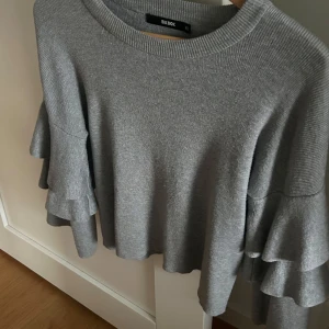 Grå tröja med volangärmar  - Säljer denna gråa tröja från Bik Bok i storlek XS. Tröjan har volangärmar och är super fin 
