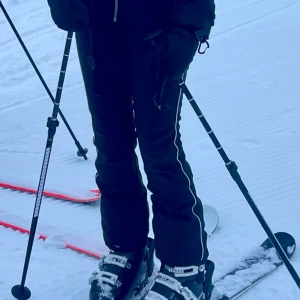 Svarta skidbyxor med vita detaljer - Snygga svarta skidbyxor med vita linjer längs benen. Perfekta för vintersport och håller dig varm i backen. Byxorna har en bootcut-stil och är högmidjade för extra komfort. Passar mig som är en och 160 på bilden 