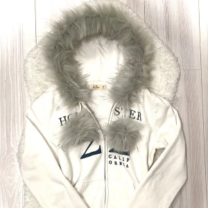 vit hollister fur zip up - handsydd därav pris, prisförslag nekas! skit snygg kofta med en väldigt mjuk päls och pom poms. nackdelen är att lite hår från pälsen går av men inget en borste ej kan borsta bort. sedan är sömnen på utsidan lite asymmetriskt men inget som påverkar användningen eller syns så mycket. 💝handtvätt med ljummet vatten då tvättmaskin + torktumlare förstör pälsen! varan finns alltid kvar tills det står SÅLD. 