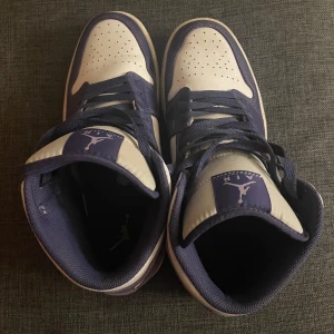 Nike Air Jordans i lila och vit (sky-purple?) - Snygga Nike Air Jordans i en stilren kombination av lila och vit. Skorna har klassisk snörning och den ikoniska Air Jordan-loggan på sidan. Perfekta för dig som vill ha en sportig och trendig look.