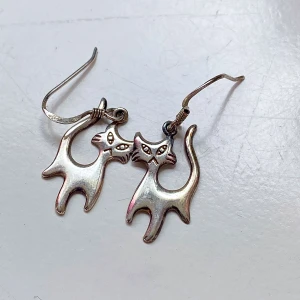 Söta kattformade örhängen i silver - Säljer ett par unika och charmiga örhängen i form av katter. De är gjorda i silver och har en stilren design med små detaljer som ger dem karaktär. Perfekta för kattälskare eller som en rolig accessoar till vardagsoutfiten. De är lätta och bekväma att bära hela dagen. stämplat 925