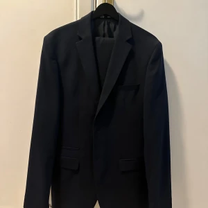 Marinblå kostym (selected homme) - Marinblå Selected homme kostym. Kavajen är i storlek L med lite längre armar samt byxorna är 34 med lite extra längd. Använt 1 gång så i väldigt fint skick! 
